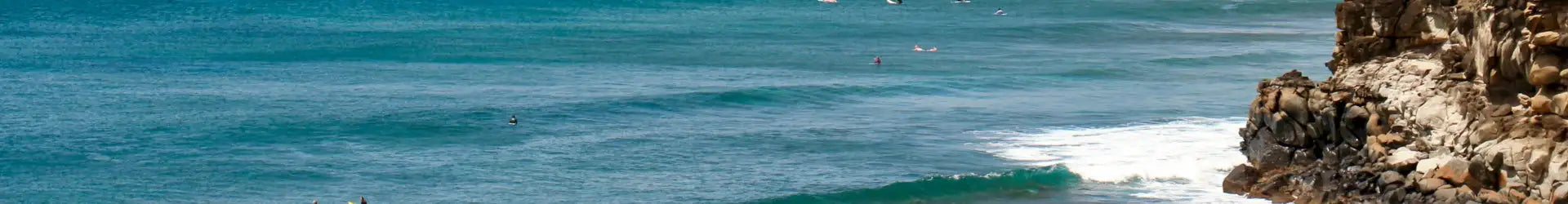Turquoise ocean waves crash against rugged, rocky cliffs.